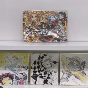 Colorful anime poster on a shelf with fiery characters in action; three framed prints sit below it.