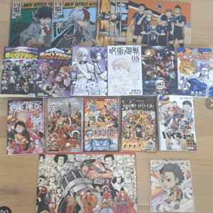 Collection of manga volumes spread on a wooden floor, featuring My Hero Academia, One Piece, and other titles.