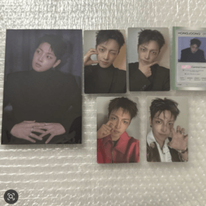 Set of glossy photo cards featuring a male idol in various poses, with a large portrait on the left and several smaller cards to the right on a textured surface.