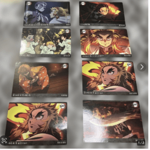 Eight Demon Slayer trading cards laid out on a blurred gray background, each card showing a different dynamic anime scene with characters like Tanjiro, Zenitsu, Inosuke and Rengoku.