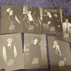 Seven black-and-white fashion portraits of male K-pop idols laid on a blue carpet, each with neon pink-green 'Season's Greetings 2022' logo at the bottom.”]} plus {