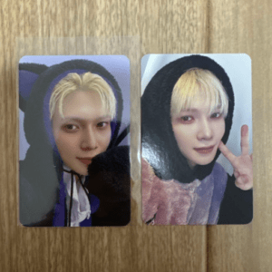 Two photo cards showing a person with blonde hair in a purple hooded jacket, placed on a wooden surface (left card close-up)./nRight card shows the same person smiling and flashing a peace sign nearby.