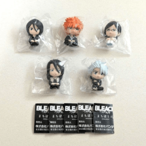 Five chibi Bleach character figurines in clear plastic bags, arranged in two rows with Bleach-branded cards laid out below.