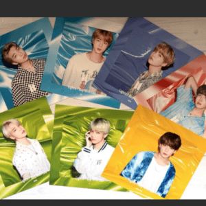 A collage of glossy portrait posters of a boy band, laid on a wooden floor with bright blue, green, yellow, and pink backgrounds.