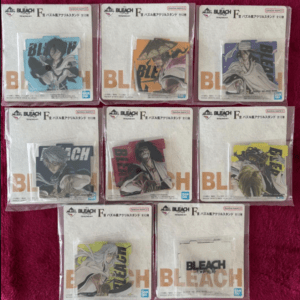 A collection of Bleach F acrylic stand packaging, each with colorful character art, laid out on a pink surface.