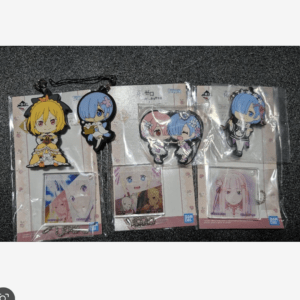 Set of anime character keychains and small acrylic charms in plastic packaging laid on a dark surface.