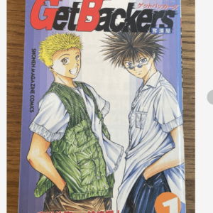 Manga cover for GetBackers featuring two smiling boys, one with blond hair in a green vest and the other with spiky dark hair in a light shirt, standing against a purple background.