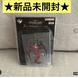 New, unopened Overlord acrylic stand figure package featuring a red-suited demon with wings, displayed against a gray fabric background.