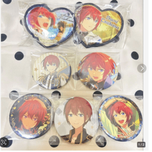 Six round anime character pins in clear packaging laid on a polka-dotted surface, featuring a red-haired male character in various poses and outfits.