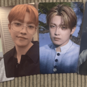 Four photocard images of the same young man with orange-blonde hair, each in a different outfit (formal, casual) and one wearing glasses, laid side by side on a textured carpet.