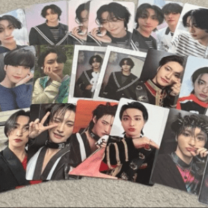A collection of glossy photo cards showing different portraits of a young male celebrity, laid out on a light carpet.
