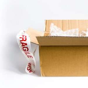 Open cardboard box with fragile sticker and bubble wrap on a white surface.
